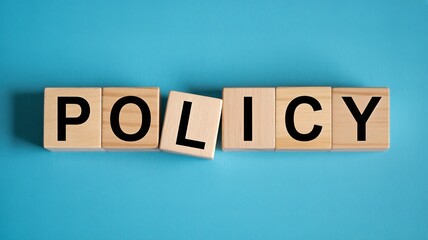 Wooden blocks spelling policy on blue background