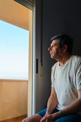 Mature man contemplating at home by open window