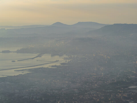 Aerial view of the hazy cityscape fading into the horizon, with distant mountains overlooking the tranquil bay, Naples, Campania, Italy.