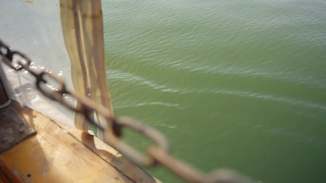 Wooden boat deck with rusty metal chain guardrails in Sea of Galilee in Israel. Pilgrim christian trip sightseeing tour on Jesus related historic and biblical sites. Navigating sailing in lake water