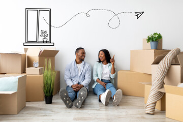 Real estate concept. Young african american couple sitting near white wall among cardboard boxes, woman pointing up at free space and dreaming together about renovation in their home