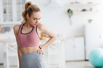 Unhappy european pretty millennial blonde woman suffering from injury and muscle pain in her side...