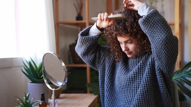 Young woman combing her beautiful curly hair