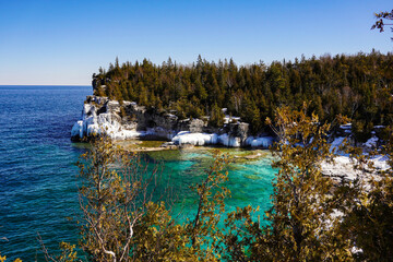 Clear blue water and forested island shoreline in Tobermory, Bruce Peninsula