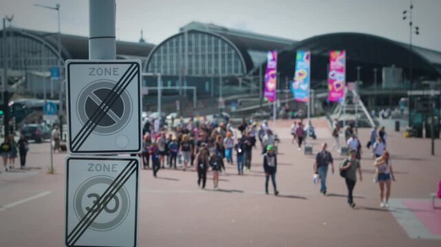 Attendees navigate lively plaza with banners and screens