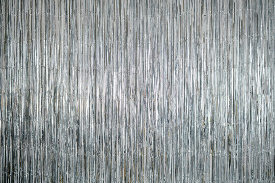 Shiny silver metallic fringe backdrop with vertical shiny strands reflecting light creating a festive background