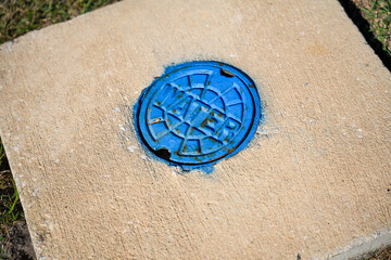 Bright Blue Steel Access Cover to a Water Main Along a Street