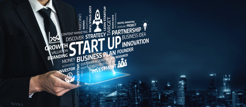 A businessman in a suit holds a digital tablet depicting startup concepts and graphics, symbolizing innovation and entrepreneurial spirit in a modern cityscape at night. Tessel - Powered by Adobe