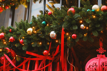 Festive green fir garland adorned with baubles, warm lights and flowing red ribbons.