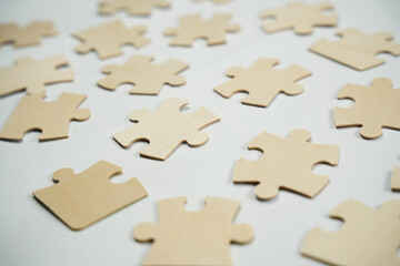 Wooden puzzle pieces are scattered on a flat white surface. They are waiting to be picked up and combined as players enjoy their time indoors.