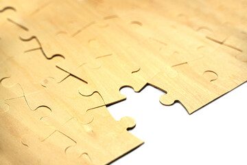 A group of puzzle pieces is laid out on a flat surface. Some pieces fit together while others are scattered nearby. The puzzle shows signs of an ongoing activity with incomplete sections.
