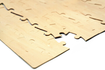 Several wooden puzzle pieces are laid out on a table. The pieces fit together and show the beginning of a puzzle arrangement during afternoon hours in a home setting.