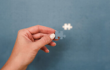 A person holds a small blue puzzle piece while looking at a space on a partially completed puzzle, illustrating the final step toward completing a large task