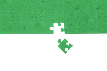 Several green puzzle pieces are arranged on a flat surface, with a visible gap symbolizing the final missing piece needed for completion.