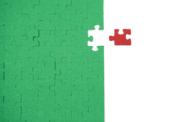 A group of puzzle pieces is placed on a flat surface. Most pieces are green, but one red piece is separated. This scene metaphorically represents a piece that does not fit, symbolizing difference or i