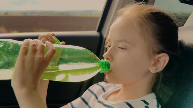Thirsty child drinking water in the car, Girl quenches her thirst during a road trip, Summer travel hydration for kids, Little kid enjoying a refreshing drink, Road trip essentials: water bottle