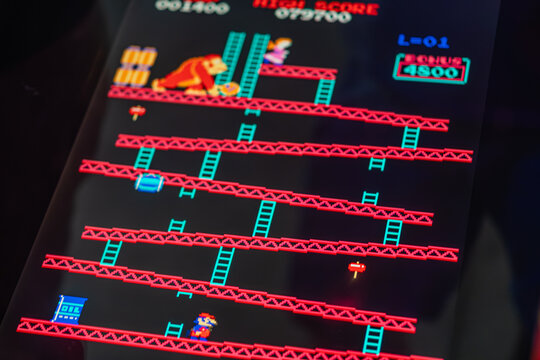 Arcade machine with Donkey Kong game, featuring pixelated 80s style graphics, Mario as main character in action pose, red, blue, black background platform pattern, - Kyiv, Ukraine - June 7, 2025