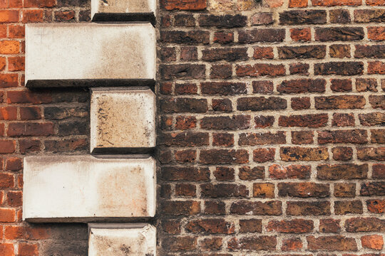 Textured red and brown brick wall with large stone architectural detailing