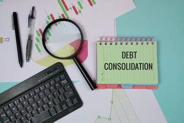 A desk setup featuring a green notebook labeled debt consolidation, a magnifier, charts, and a keyboard, illustrating financial analysis, budgeting, and planning for debt reduction and financial goals