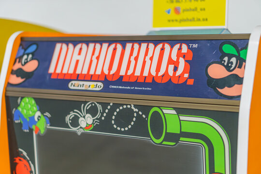 Vertical arcade game cabinet with a vibrant Mario Bros design featuring characters Mario and Luigi in comic book style art, with soft shadows from overhead lighting - Kyiv, Ukraine - June 7, 2025