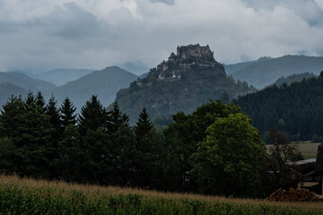 An imposing medieval fortress, Hochosterwitz Castle, sits majestically atop a steep, forested limestone hill.