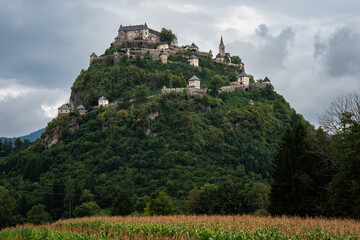 An imposing medieval fortress, Hochosterwitz Castle, sits majestically atop a steep, forested limestone hill.