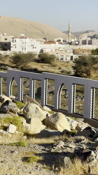 Sacred burial ground of the martyrs (Shuhada) of the historic Badr cemetery and battlefield, featuring a monument engraved with their names, surrounded by a desert mountain town landscape.