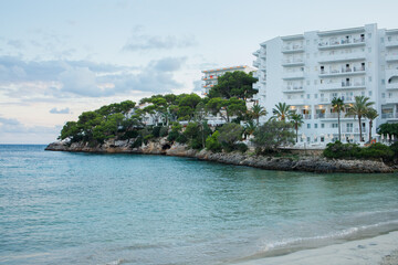 White hotel building and empty Cala Ferrera beach in the evening panoramic view. Cala D'or on Mallorca in Spain.