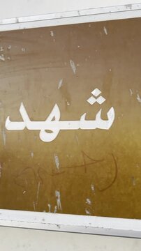 Close-up view of the Arabic Maqbara Shuhada Badr sign in Madinah, highlighting Islamic heritage, historic martyr cemetery identity, and religious travel symbolism for educational and documentary use.