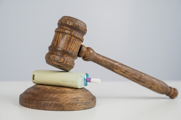 Judge's gavel hits e-cigarette. Smoking ban. Tobacco heating systems. 