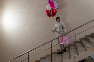 Caucasian man with pink balloons and bag on staircase