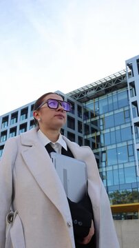 Vertical screen young woman holding laptop walking toward office building feeling nervous before job interview starting her first career after university