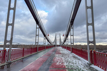  A pedestrian bridge blanketed in fresh snow creates a quiet winter scene within the urban landscape of Kyiv, Ukraine.
