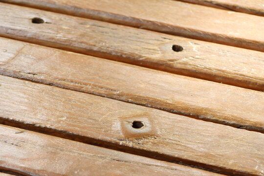 Close-up view of aged wooden slats, highlighting the natural texture, grain patterns, and circular indentations from fasteners