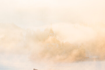 Mariä Himmelfahrt Kirche auf der Insel bei Bled nahezu vollständig vom goldenen Morgennebel...