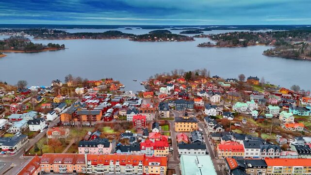 Low-rise colorful beautiful buildings in the cityscape of Vaxholm, Sweden. Multiple islets on the grey waterscape of Lake Malar at backdrop.
