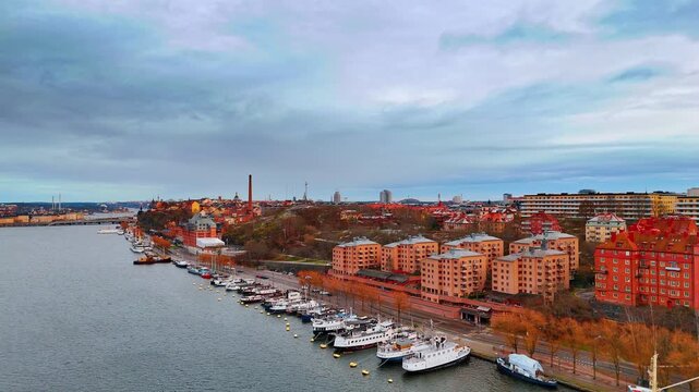 Multiple diverse vessels stand at the quay on Lake Malar. Footage along the cityscape of Stockholm, Sweden on gloomy day.