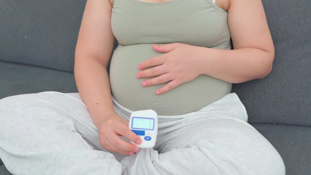 Pregnant woman in her eighth month measuring blood sugar with a portable glucometer. A calm, realistic everyday scene highlighting maternal health, prenatal care, and gestational diabetes management