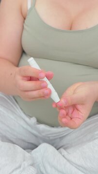 Pregnant woman in her eighth month measuring blood sugar with a portable glucometer. A calm, realistic everyday scene highlighting maternal health, prenatal care, and gestational diabetes management