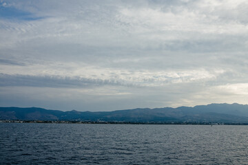 Characteristic features of a Greek island include dry terrain, strong sunlight, blue sea, rocky coastline, and Mediterranean vegetation.