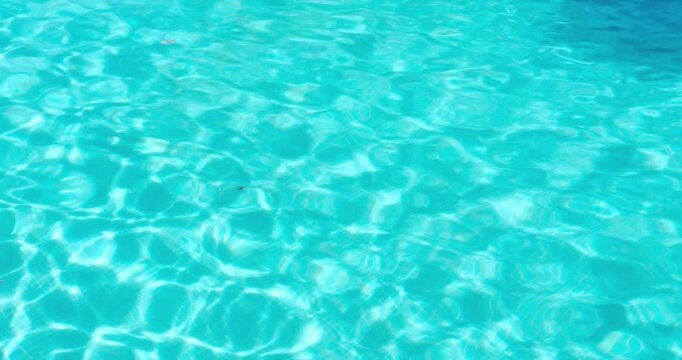 PORTOCOLOM, MALLORCA, SPAIN - OCTOBER, 2025: Gentle ripples move across the surface of a swimming pool, reflecting the sun's light during a holiday.