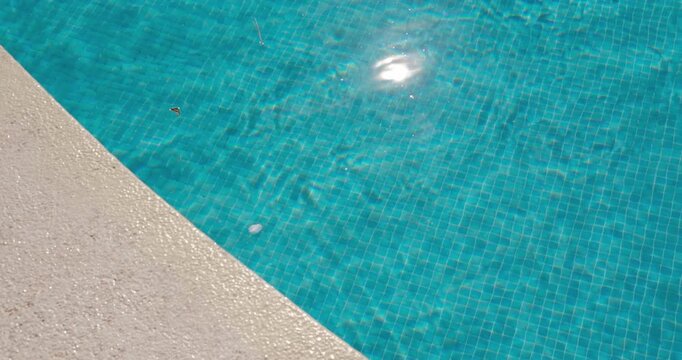 PORTOCOLOM, MALLORCA, SPAIN - OCTOBER, 2025: Sunlight creates dancing reflections on the surface of the pool, small ripples move across the blue water in close up.