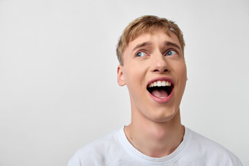 Surprised, astonished man looks upward with a wide smile against a clean background, conveying curiosity and excitement suitable for marketing, ads, and media about discovery and cheerful reactions