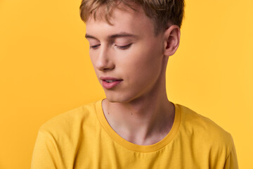 Fototapeta premium Young man wearing a bright yellow shirt stands against a matching yellow background, presenting a minimal, calm vibe with clean lines and studio lighting in a contemporary mood. Perfect for fashion,