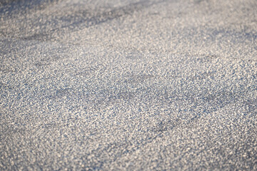 Deicing chemicals on the street in winter, closeup. Salt grains on icy sidewalk, asphalt with rock salt in cold season. Slippery road sprinkled with technical salt and calcium. Prevent slipping