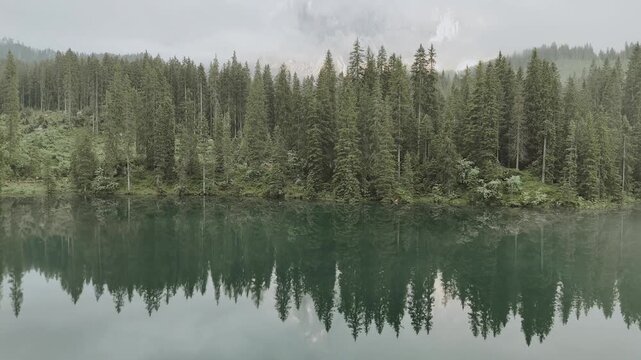 Survol en drone d'un lac de montagne paisible avec brume matinale et reflets de for&ecirc;t. 
