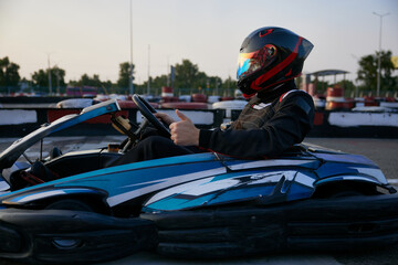 A focused racer grips the steering wheel of a go-kart, ready to hit the track