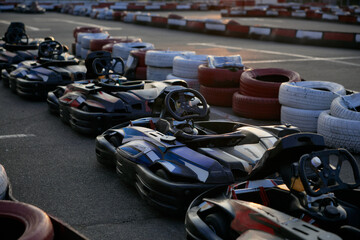 A vibrant go-karting track featuring parked karts lined up along a red and white tire barrier