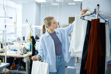 A fashion designer skillfully organizing an array of fabrics within her studio space