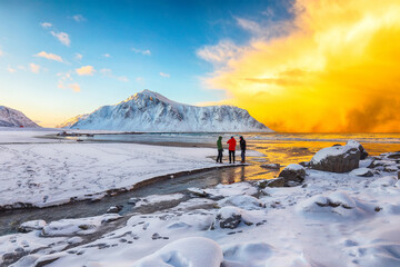 Group of tourist looking  on Skagsanden beach with illuminated clouds during sunrise